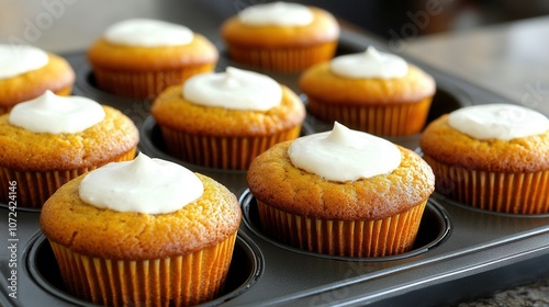 Freshly baked cupcakes with creamy frosting in baking tray