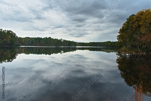 A glassy smooth reservoir pond allows the beautiful fall trees along the shore to cast an amazing reflection on the water.