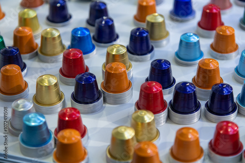 Close-up view of group of various multi coloured empty aluminium packages for coffee capsules (or coffee pods) lying on grey table. Coffee tool background. Copy space. Recyclable material theme.