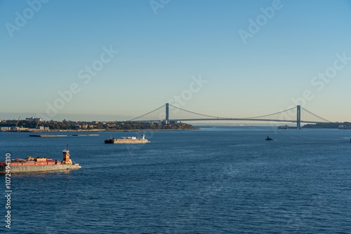 ships sailing towards Verrazzano-Narrows Bridge with urban architecture and sky in the background photo