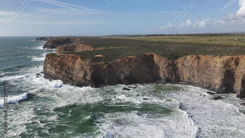 Drone ascends above huge coastal cliffs and giant ocean surf. Alentejo region, Portugal 