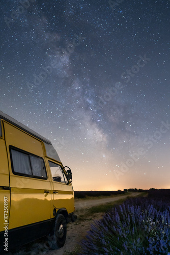 Retro yellow camper van parked under the starry sky in Valensole lavender fields in Provence, France. Long exposure astrophotography