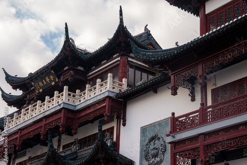 A traditional building in Shanghai's old town features ornate eaves, red and white colors, and a sign with Chinese characters, showcasing classical design. photo