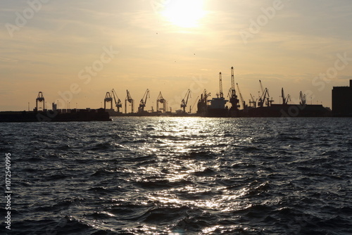 Industrial Port Cranes Silhouetted Against Sunset on the Waterfront photo