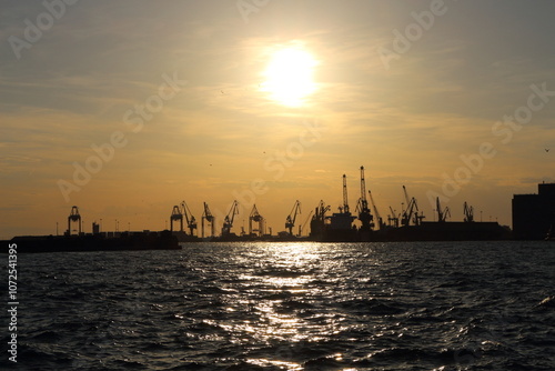 Industrial Port Cranes Silhouetted Against Sunset on the Waterfront photo