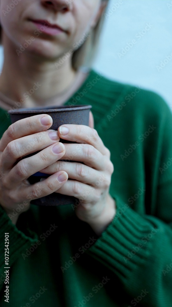 hands of a sick woman in a green sweater holding a cup with a hot drink
hands of a sick woman in a green sweater holding a cup with a hot drink