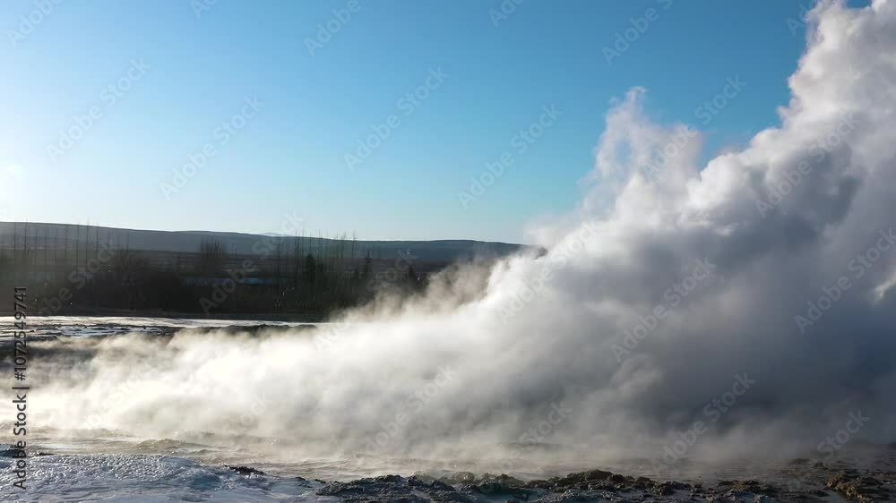 Witness the powerful eruption of a geyser at the Geysir geothermal area in Iceland, surrounded by stunning landscapes under a clear blue sky. Witness the powerful eruption of a geyser at the Geysir geothermal area in Iceland, surrounded by stunning landscapes under a clear blue sky.