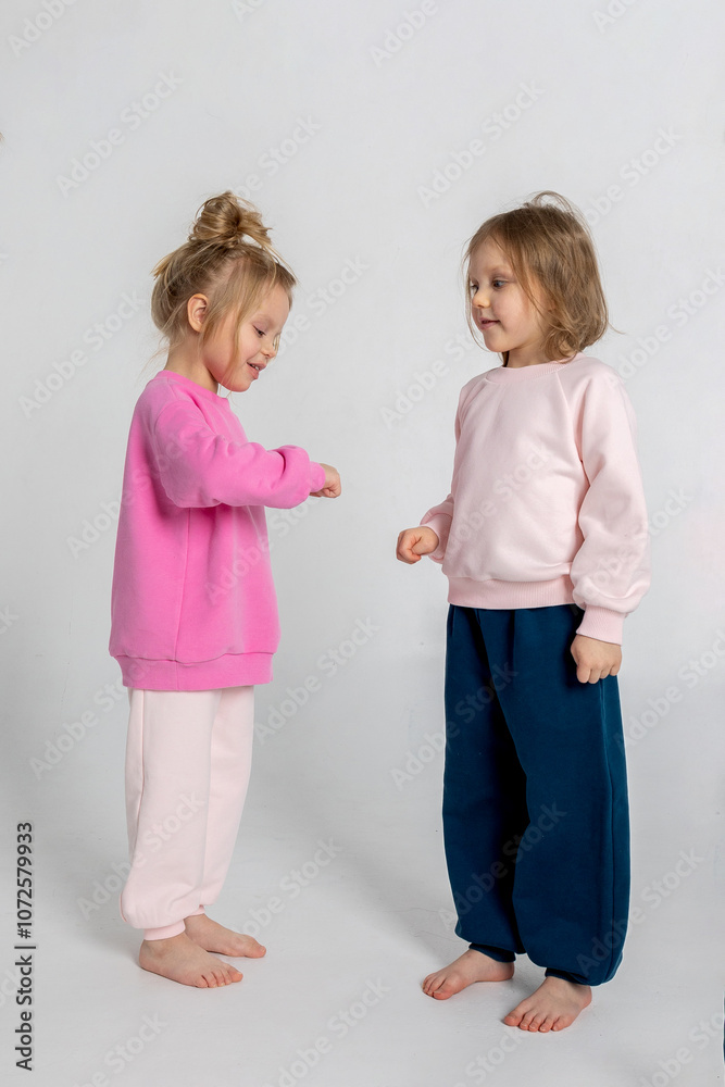 Two funny cute girls playing and having fun. Children with smiles and funny emotions on a light background. Vertical photo. High quality photo