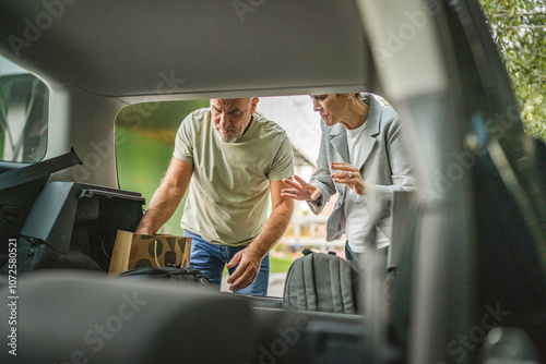 Senior mature couple pack bags in car trunk for a journey