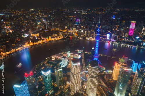 Shanghai's skyline at night features the illuminated Oriental Pearl Tower, the Huangpu River, and the historic Bund, showcasing modern and historic architecture.