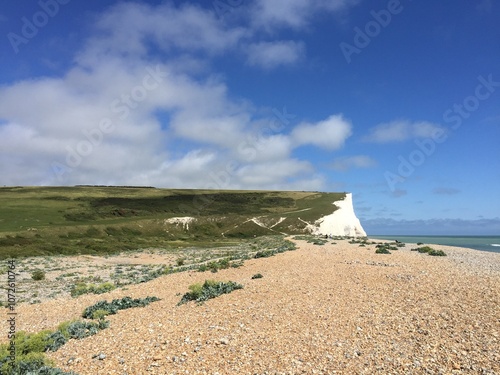 Pebble beach at Cuckmere Haven in Sussex, England, with a view of the iconic white chalk cliffs and the Seven Sisters cliffs in the background on a clear day. photo