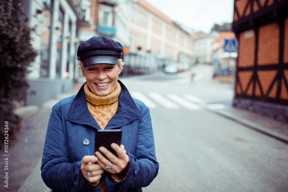 Smiling stylish senior mature woman using smartphone on city street Smiling stylish senior mature woman using smartphone on city street