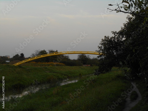 Yellow, arched pipeline over the river.