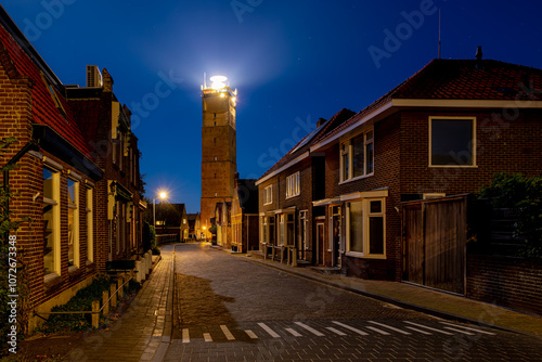 Night cityscape, The Vuurtoren Brandaris with illuminated lighthouse and stars, Houses on the Dutch Wadden Sea, A municipality and an island in the northern, Friesland, West-Terschelling, Netherlands. photo