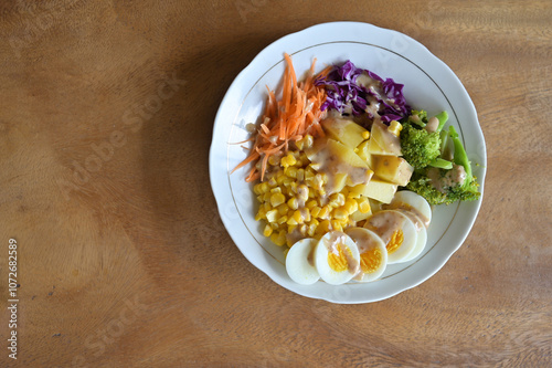 Delicious vegetable salad with chicken egg and corn. Healthy food. Flay lay view on wooden table