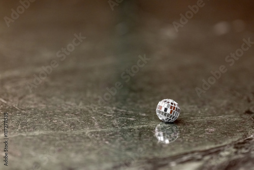 A small disco ball on a stone table. Club concept. New Year decoration
