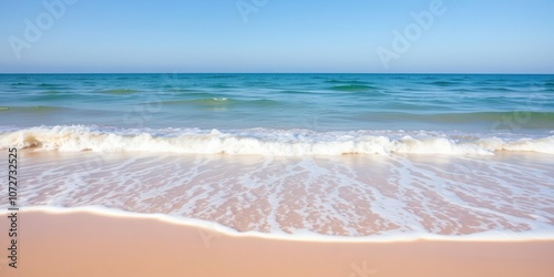 A serene image of gentle waves lapping against a sandy beach, with a clear blue sky overhead, holiday, scenic, shore