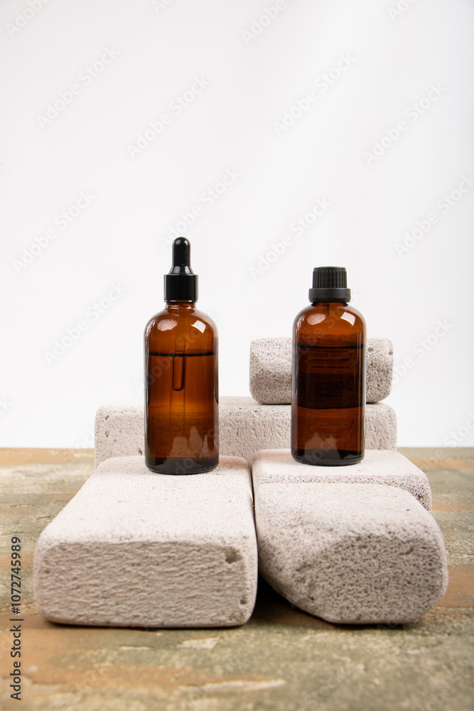 Amber Glass Dropper and Screw Cap Bottles Displayed on Stone Pedestals Amber Glass Dropper and Screw Cap Bottles Displayed on Stone Pedestals