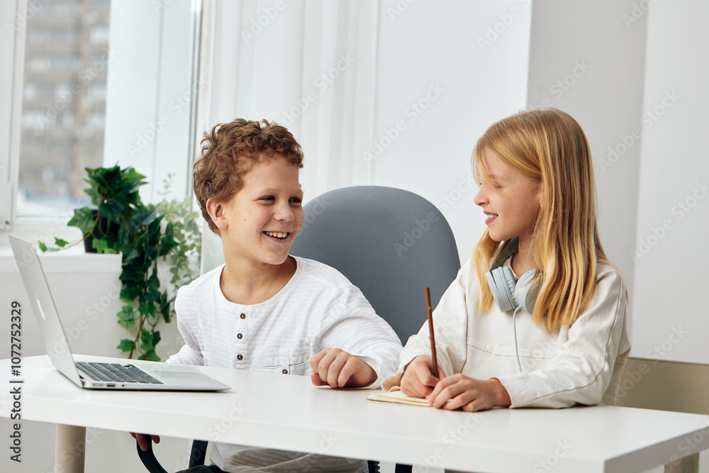Happy Caucasian boy and girl studying together at home using laptops and headphones for online elearning They are sitting at a table in the living room, fully concentrated and immersed in their Happy Caucasian boy and girl studying together at home using laptops and headphones for online elearning They are sitting at a table in the living room, fully concentrated and immersed in their