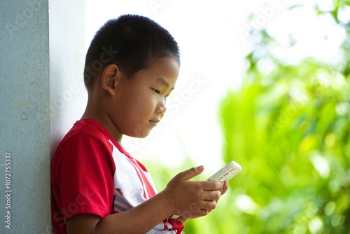 Smiling young boy holding mobile phone outdoors