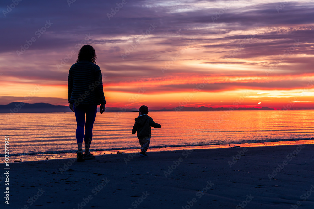 Mother and Child Walking On Beach During Vibrant Sunrise Mother and Child Walking On Beach During Vibrant Sunrise