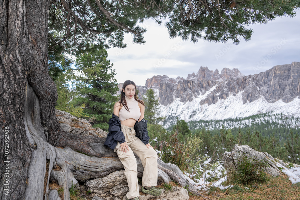 Naklejka premium Woman sitting under the tree enjoy the view of alpine mountain landscape snowy.
