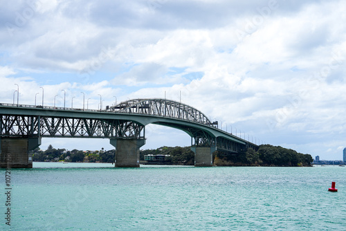 Majestic View of the Iconic Suspension Bridge Spanning the Clear Blue Waters under a Dramatic Cloudy Sky, Perfect for Travel and Infrastructure Themes