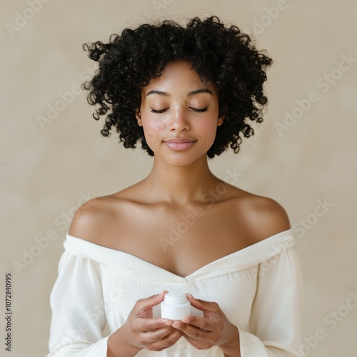 A young woman holding skincare cream, promoting beauty and self-care concepts. photo