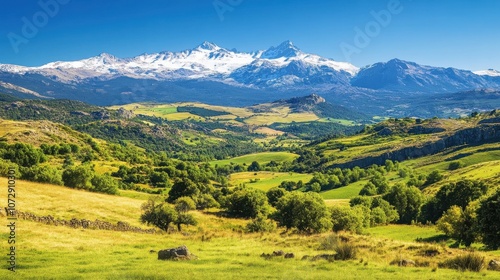 Majestic view of the snow-capped Sierra de Gredos mountains amidst green valleys under a clear blue sky in Extremadura