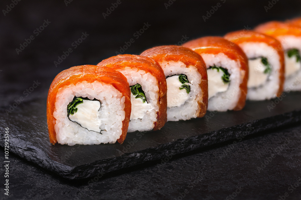 Japanese rolls, Philadelphia sushi with salmon and cream cheese on a black background. Japanese rolls, Philadelphia sushi with salmon and cream cheese on a black background.