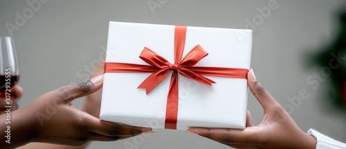 A person hands a beautifully wrapped gift adorned with a red ribbon, symbolizing celebration and generosity.