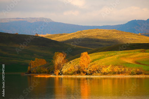 Lake in the mountains. Yellow autumn trees reflected in the water.