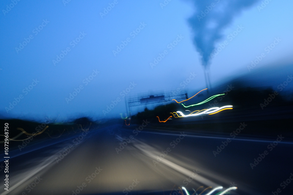 Obraz premium Light trails on the highway at dawn, smoke from a chimney, swaying, long exposure / 明け方の高速道路のライトの軌跡 煙突から出る煙 振れる 長時間露光