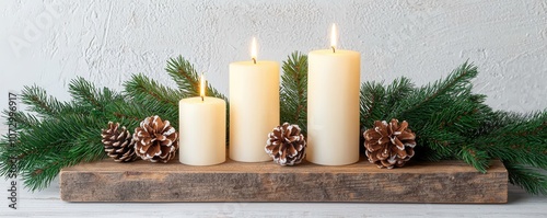 A cozy winter arrangement featuring three white candles, pinecones, and evergreen foliage on a rustic wooden base photo