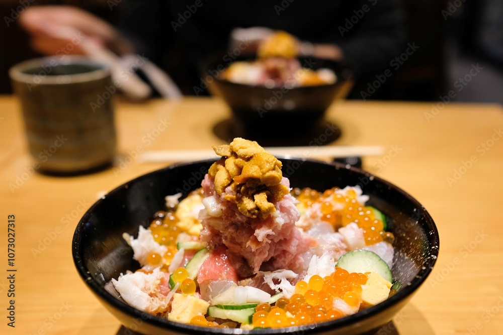 Two bowls of chirashi-don with sushi rice, sashimi off-cuts, salmon roe, sea urchin and fresh vegetables (onion and cucumber) at Sushi Tokyo Ten, a restaurant in Shinjuku — Tokyo, Japan Two bowls of chirashi-don with sushi rice, sashimi off-cuts, salmon roe, sea urchin and fresh vegetables (onion and cucumber) at Sushi Tokyo Ten, a restaurant in Shinjuku — Tokyo, Japan