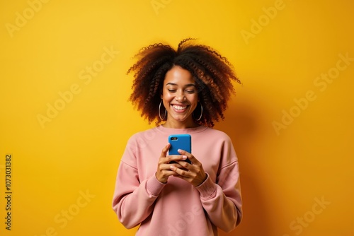 Smiling woman using smartphone against vibrant yellow background photo