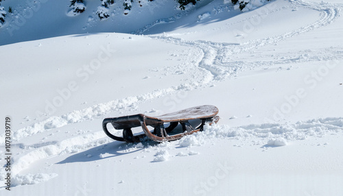 Wooden sled on snow-covered hill with tracks and winter scenery