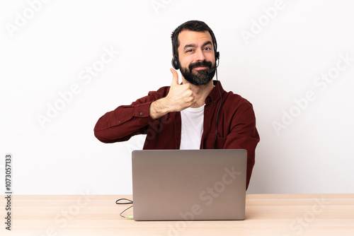 Telemarketer caucasian man working with a headset and with laptop giving a thumbs up gesture.