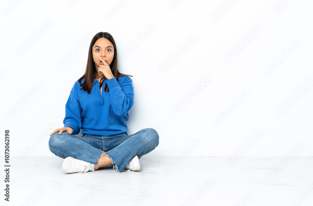 Young mixed race woman sitting on the floor isolated on white background surprised and shocked while looking right Young mixed race woman sitting on the floor isolated on white background surprised and shocked while looking right