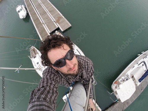 Man to the top of the mast of a sailing boat