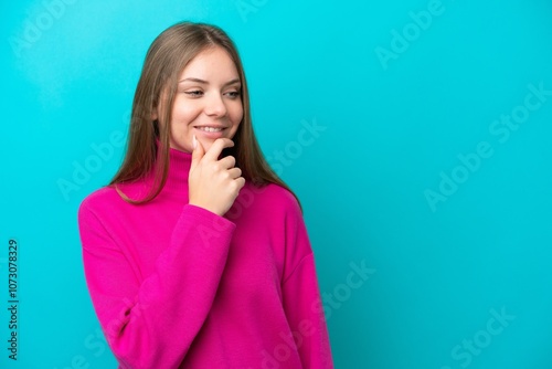 Young Lithuanian woman isolated on blue background looking to the side and smiling