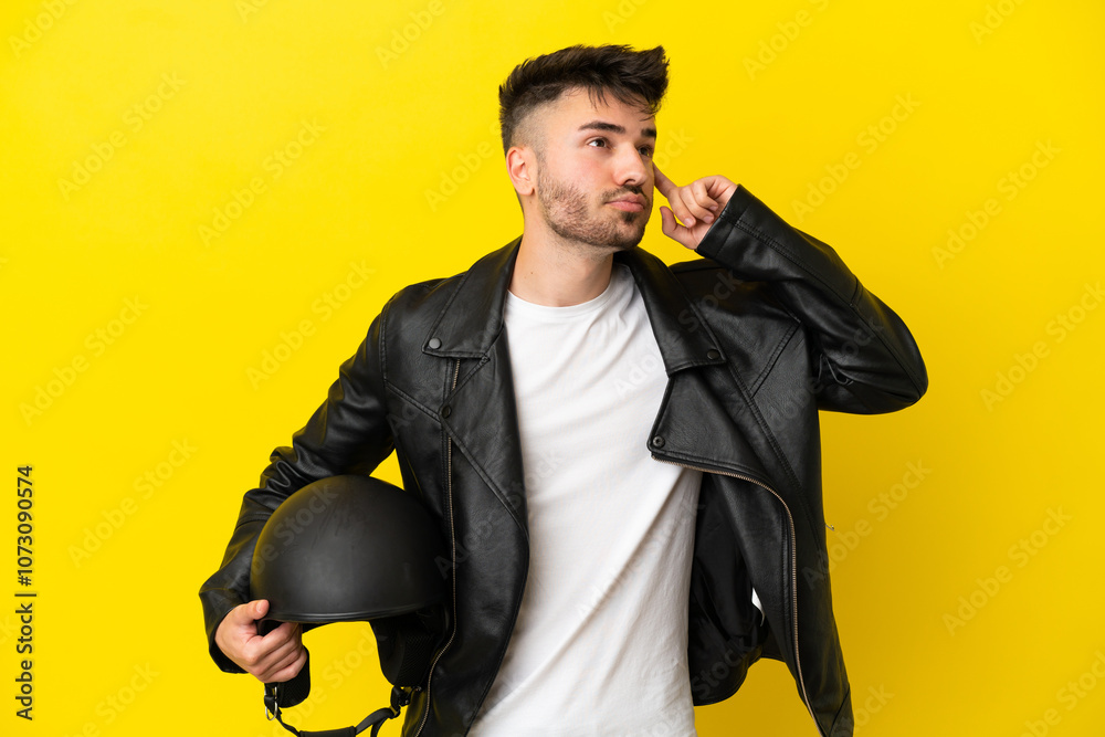 Young caucasian man with a motorcycle helmet isolated on yellow background having doubts and thinking Young caucasian man with a motorcycle helmet isolated on yellow background having doubts and thinking