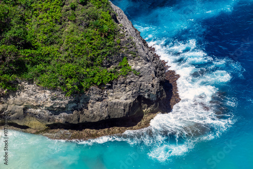 Majestic cliffs stand tall as powerful waves crash against them, sending sprays of mist into the air. A stunning dance of nature's strength and beauty in Nusa Penida of Bali.