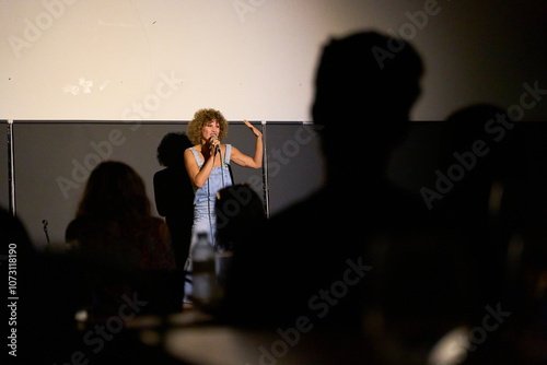 Foto Caucasian female performer with curly hair delivering a monologue on stage in a