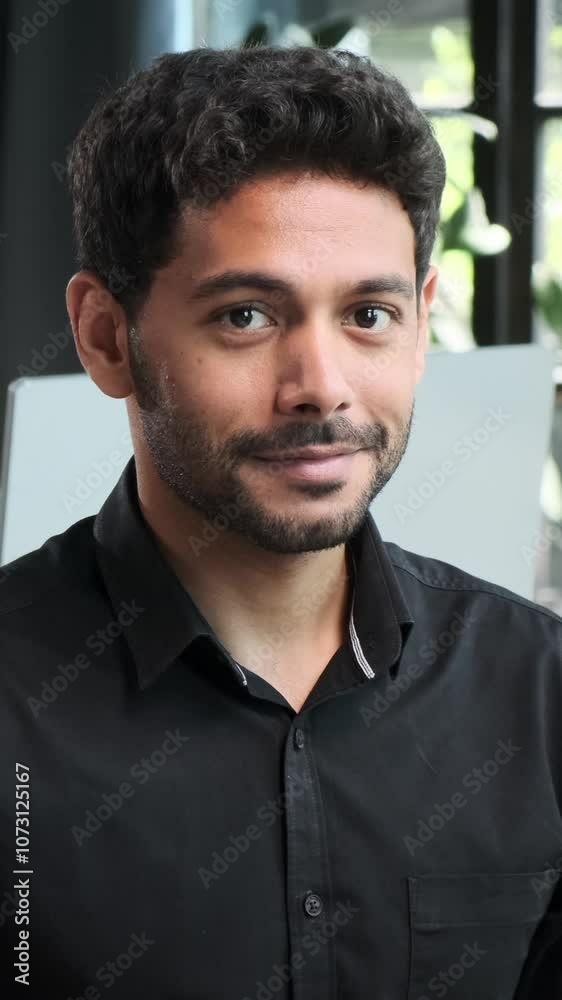 Portrait of a friendly Middle Eastern young adult man working in the office. Concept of a positive entrepreneur or executive. Vertical video.