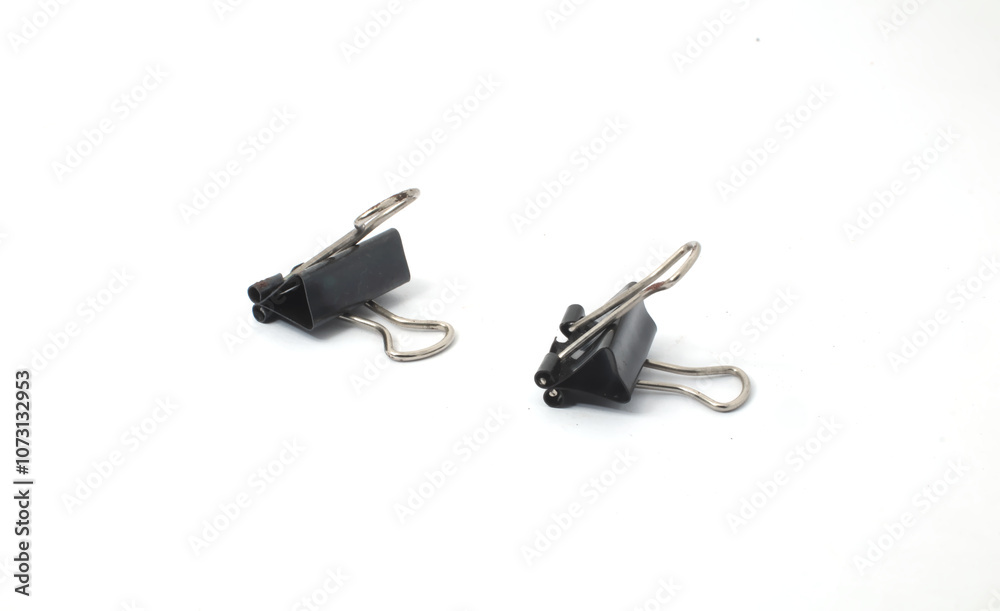Separated Binder Clips. Two small black binder clips spaced apart, creating a minimalistic and isolated view. Separated Binder Clips. Two small black binder clips spaced apart, creating a minimalistic and isolated view.