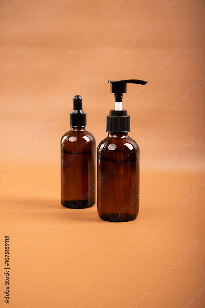 Amber Glass Pump and Dropper Bottles for Skincare and Essential Oils on Neutral Background