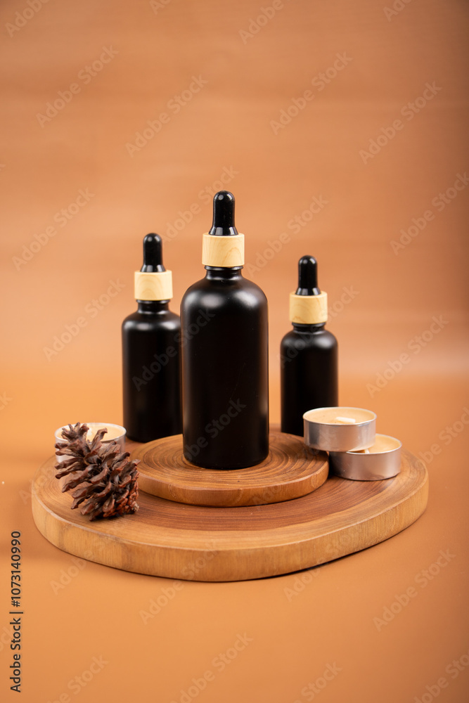 Black Dropper Bottle with Candle and Cinnamon on Woven Mat for Spa and Skincare Black Dropper Bottle with Candle and Cinnamon on Woven Mat for Spa and Skincare