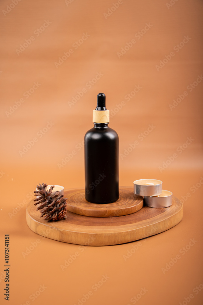 Black Dropper Bottle with Candle and Cinnamon on Woven Mat for Spa and Skincare Black Dropper Bottle with Candle and Cinnamon on Woven Mat for Spa and Skincare