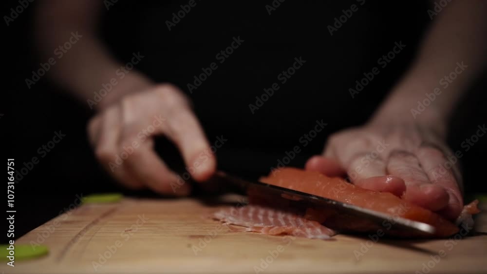 Close-Up of Hands Slicing Fresh Salmon Fillet on a Dark Background